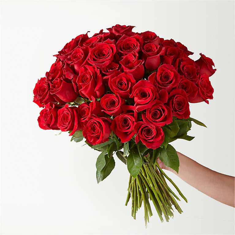 Fresh long-stemmed red roses arranged in a sleek vase, creating a stunning centerpiece for any occasion.