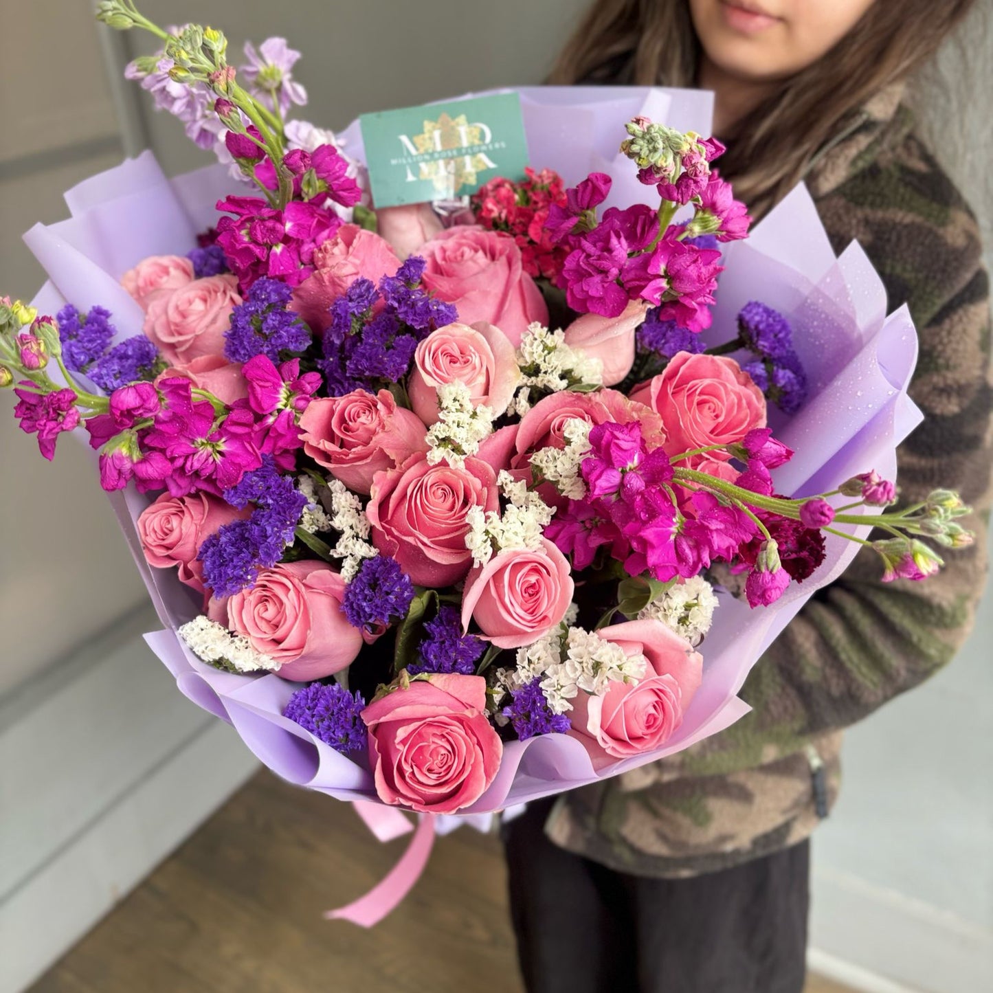 Florist arranging a colorful bouquet of fresh flowers in a cozy flower shop with vases and greenery in the background.
