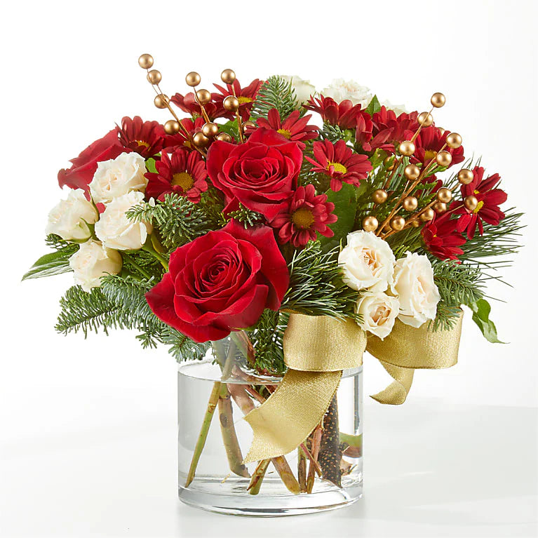 Festive sleigh Christmas floral arrangement featuring vibrant red roses, carnations, cream spray roses, hypericum berries, golden accents, and fresh greenery, arranged in a decorative white sleigh with gold snowflake details. Perfect for holiday decor or gifting