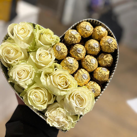 Heart-shaped box filled with light green roses and gold Ferrero Rocher chocolates.