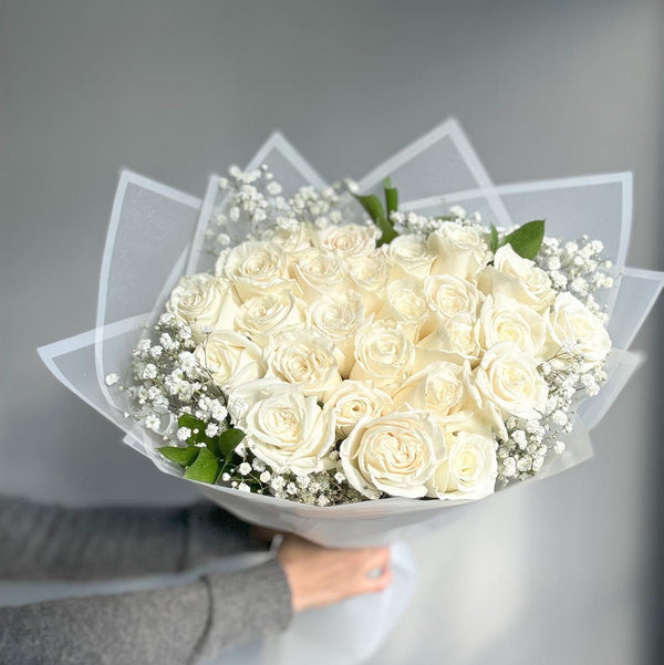 Bouquet of white roses held by a person against a gray background