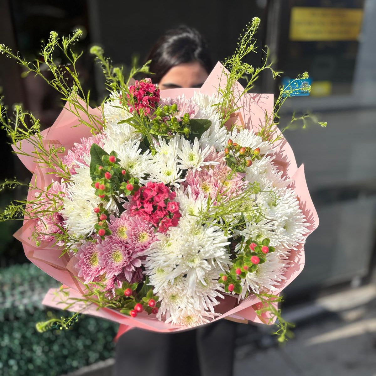 Person holding a bouquet of flowers with a blurred background