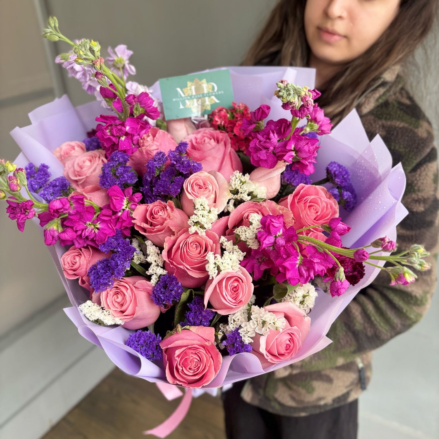 Person holding a bouquet of pink and purple flowers