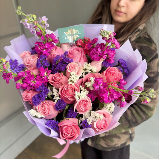 Person holding a bouquet of pink and purple flowers