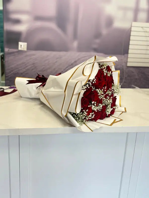 Bouquet of red roses with white accents on a light surface