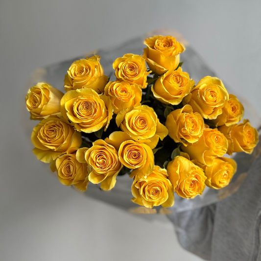 Bouquet of yellow roses in a clear vase on a light gray background