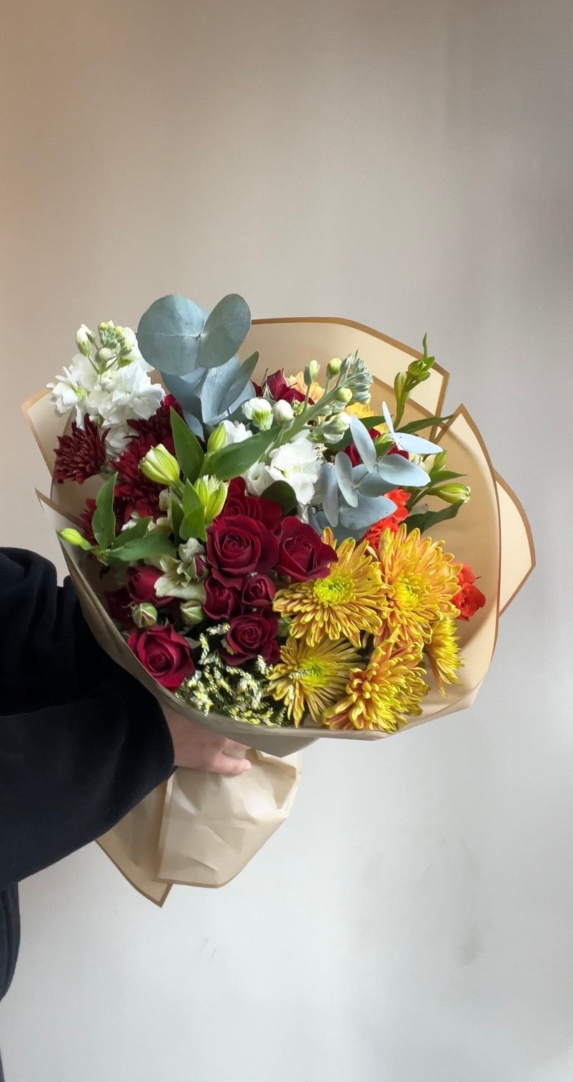 Bouquet of flowers wrapped in brown paper on a white background