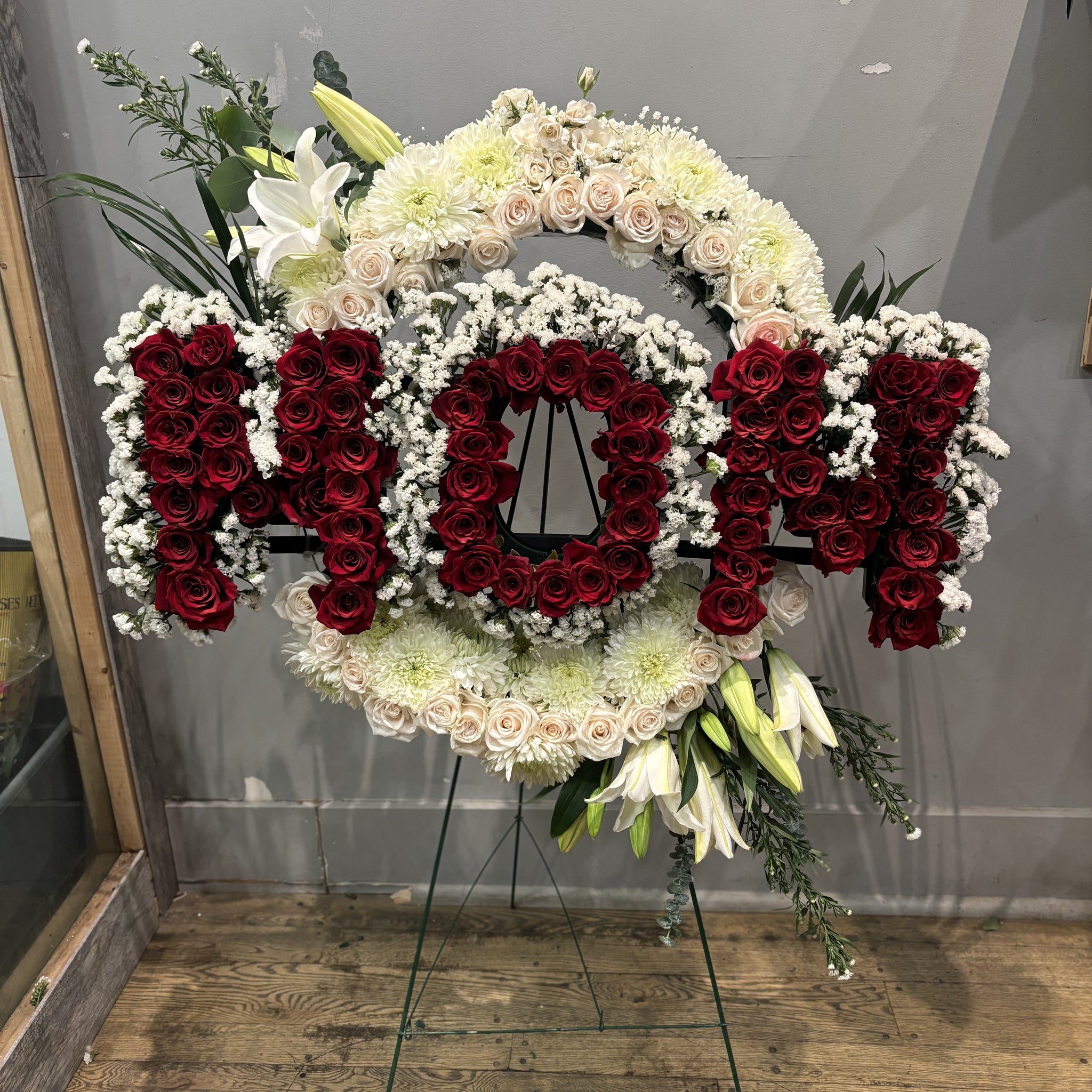 Floral arrangement with 'Mom' in red and white flowers on a stand.