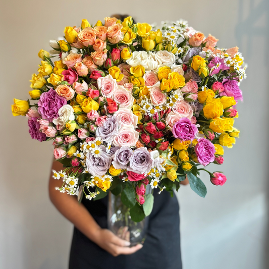 Bouquet of colorful flowers held by a person against a neutral background