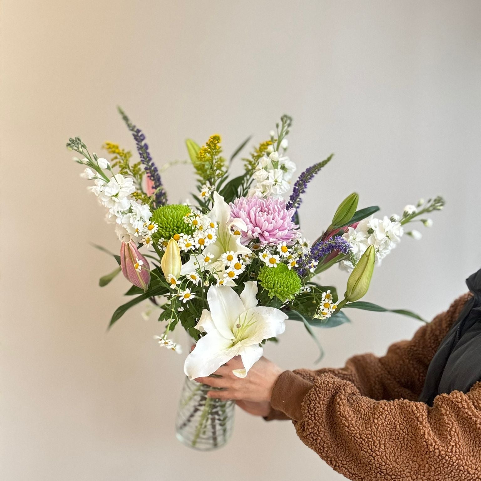Person holding a bouquet of flowers against a plain background
