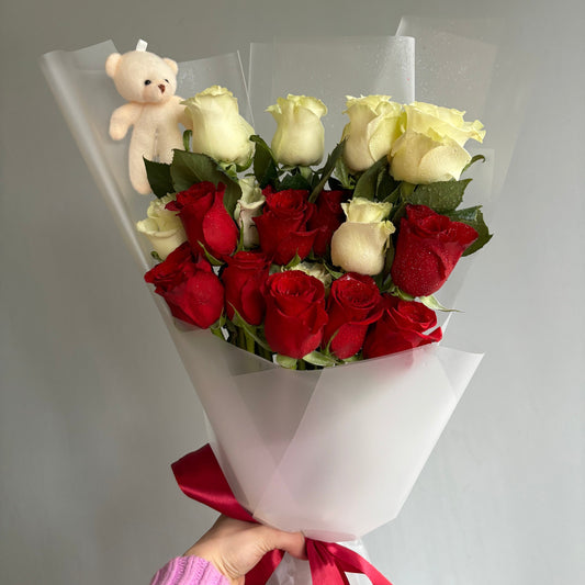 A charming arrangement of 12 red and white roses accompanied by a cute plush bear, presented in a minimalist style. The bouquet is perfect for expressing love and affection on various occasions.