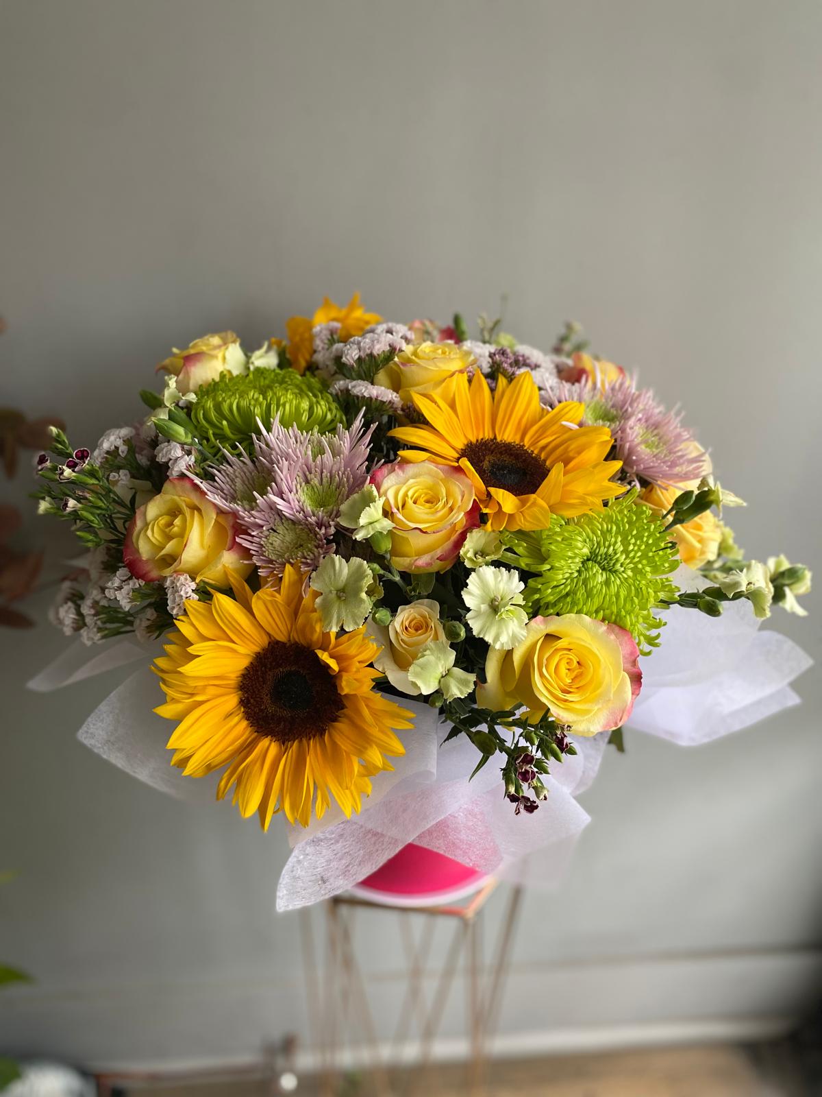 Bouquet of flowers with sunflowers and roses on a gray background