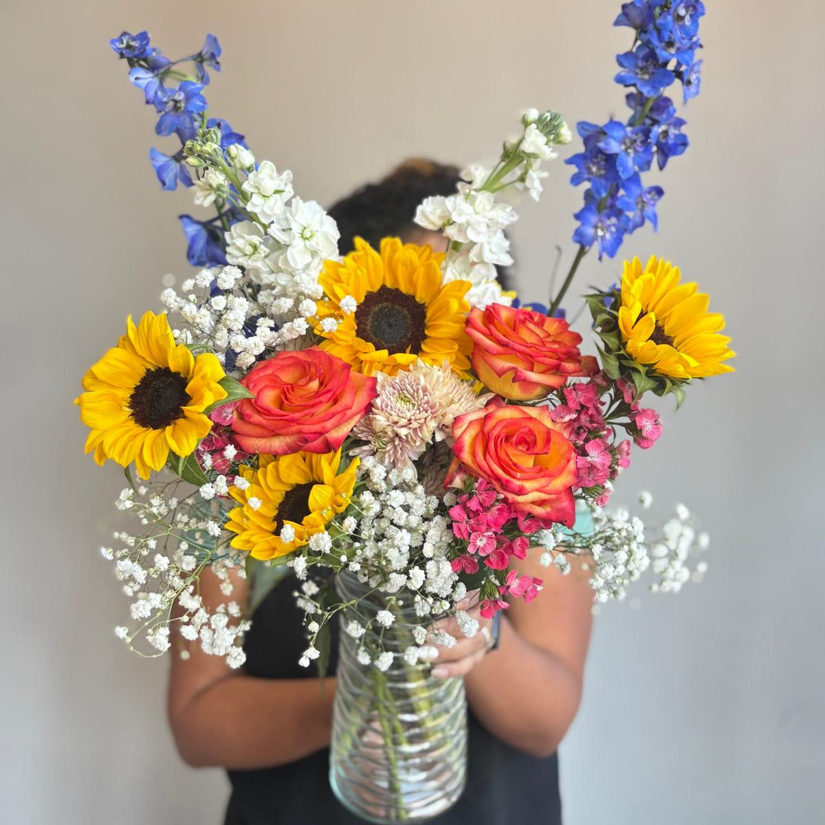 Person holding a vibrant bouquet of flowers against a plain background