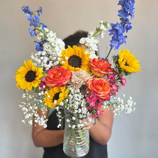 Person holding a vibrant bouquet of flowers against a plain background