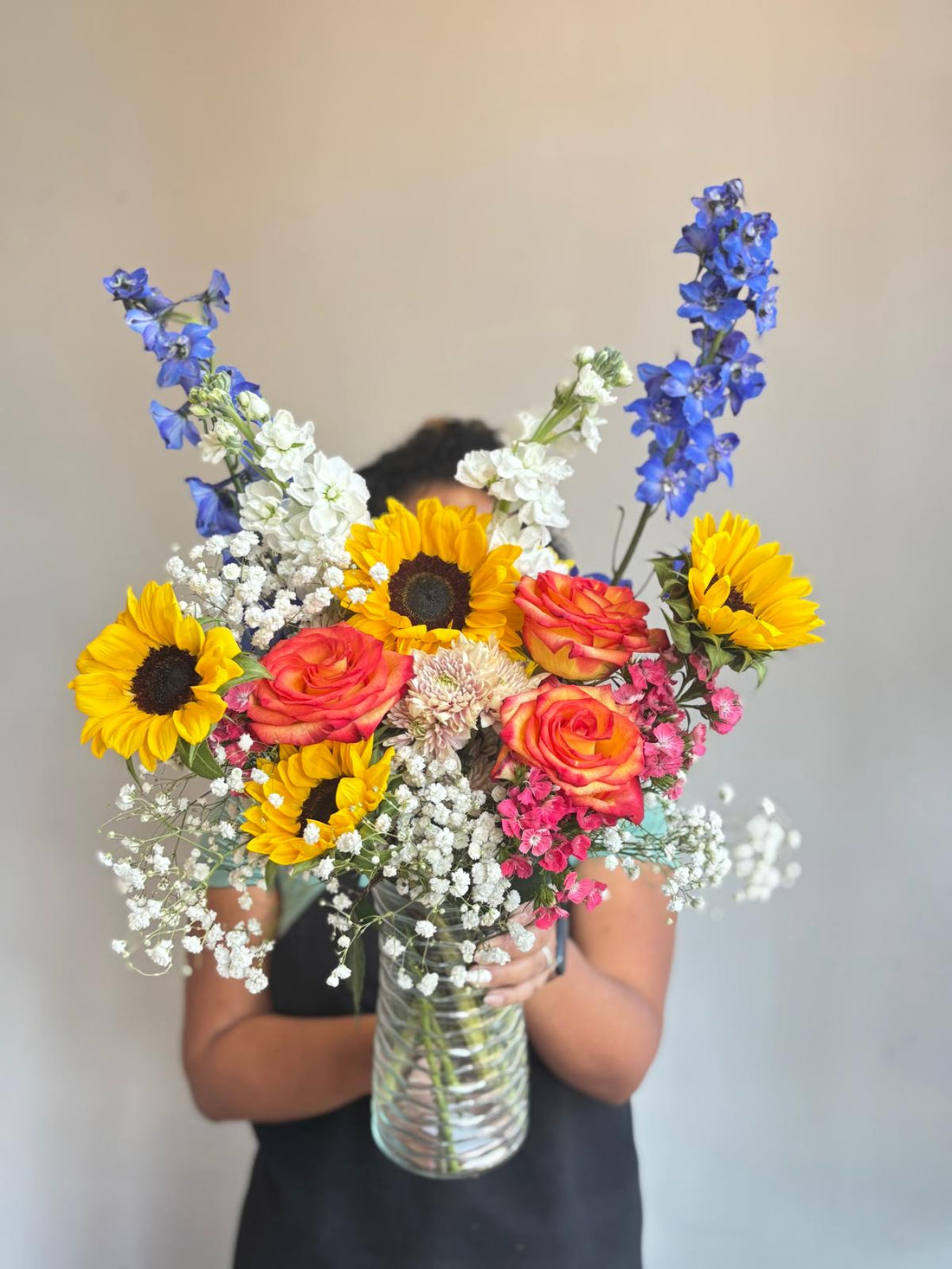 Person holding a vibrant bouquet of flowers against a plain background