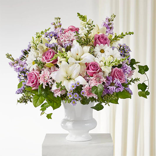 Elegant funeral flower arrangement with white lilies, pink roses, snapdragons, and stock in a deluxe bouquet for sympathy and memorial services.