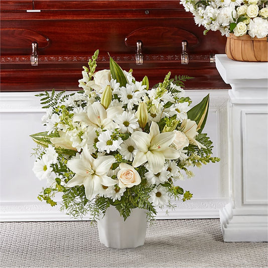 Bouquet of white flowers in a vase in front of a casket