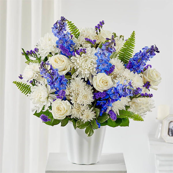 Peace of Mind Urn Arrangement with white lilies, roses, snapdragons, and greenery designed to surround a cremation urn at a funeral or memorial service