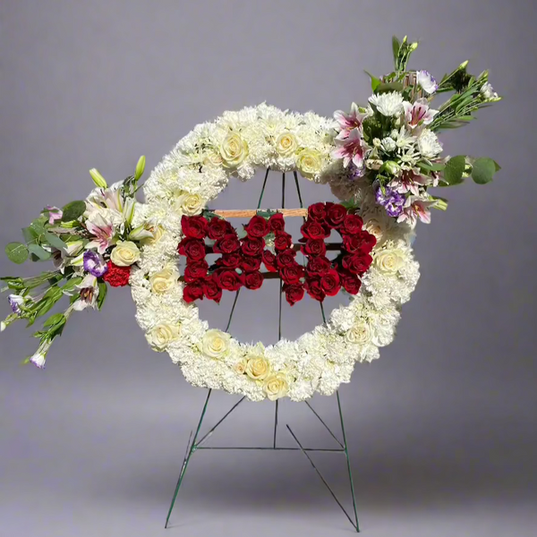 Custom funeral wreath made with a variety of fresh flowers, including lilies, roses, and greenery, designed to honor and remember a loved one. 