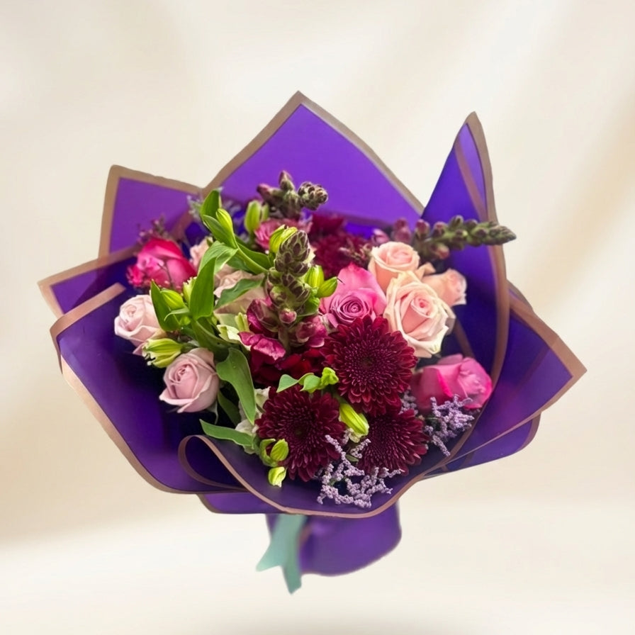 Bouquet of flowers wrapped in purple paper on a light background