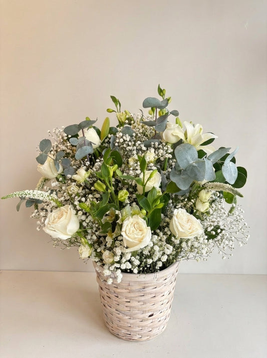 Bouquet of white flowers in a woven basket on a light background