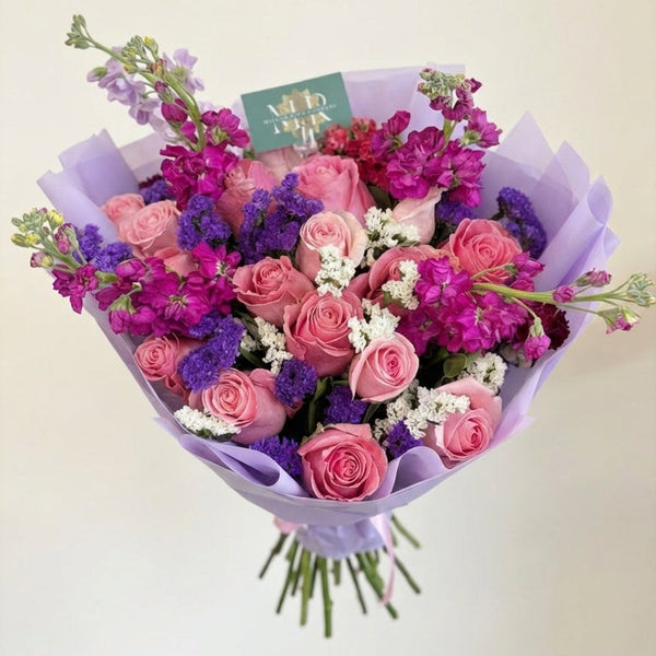 Bouquet of pink and purple flowers with a visible brand tag on a light background