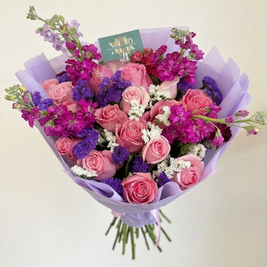 Bouquet of pink and purple flowers with a visible brand tag on a light background