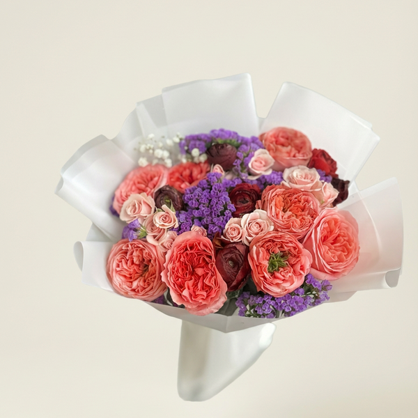 Bouquet of flowers wrapped in white paper on a light beige background