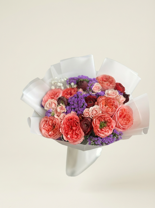 Bouquet of flowers wrapped in white paper on a light beige background