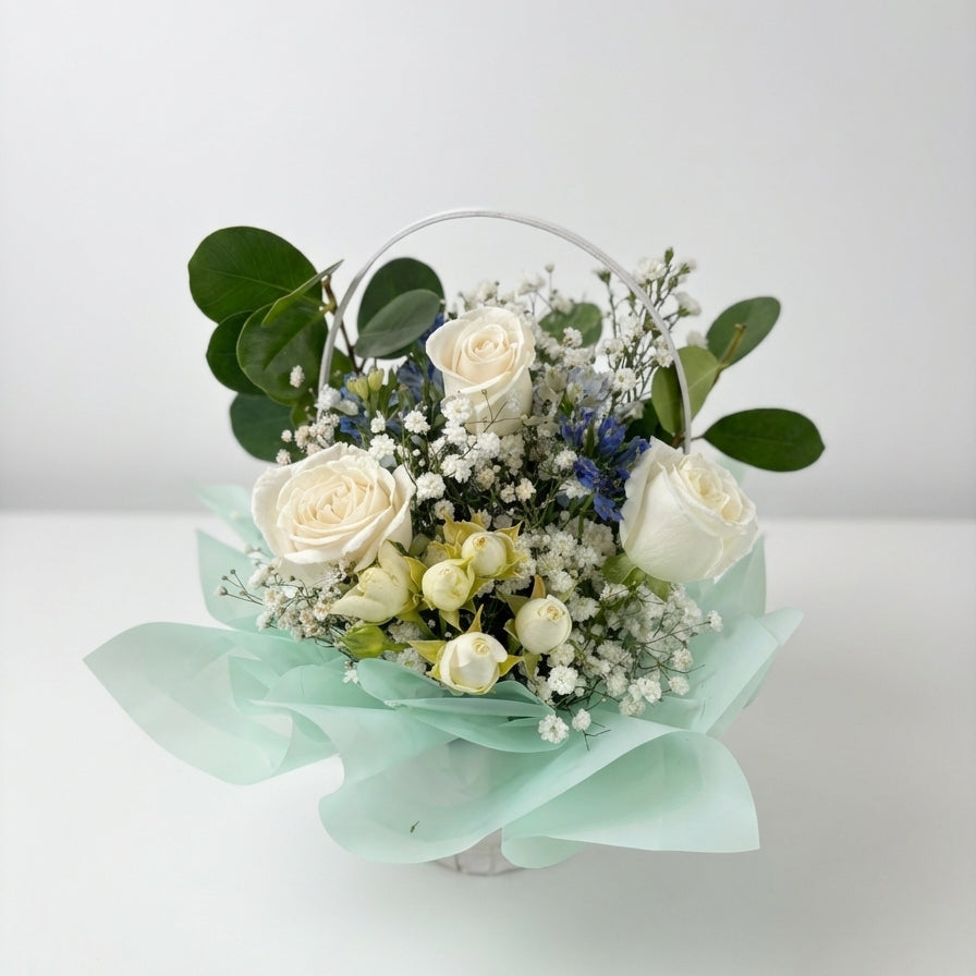 Bouquet of white roses and greenery in a transparent container on a light background
