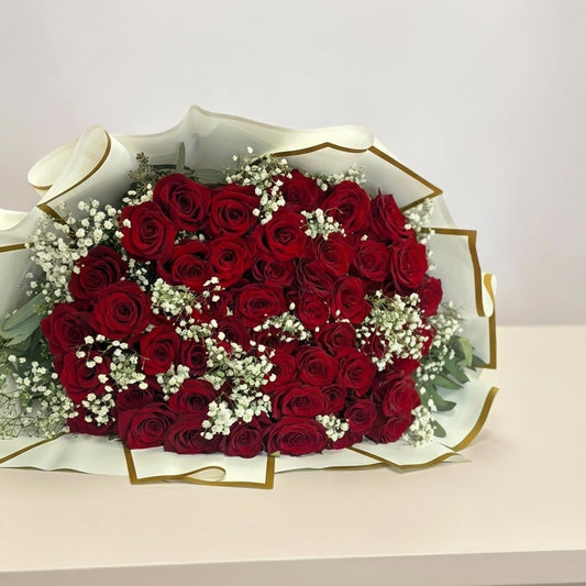 Bouquet of red roses with white flowers in a decorative box on a light background