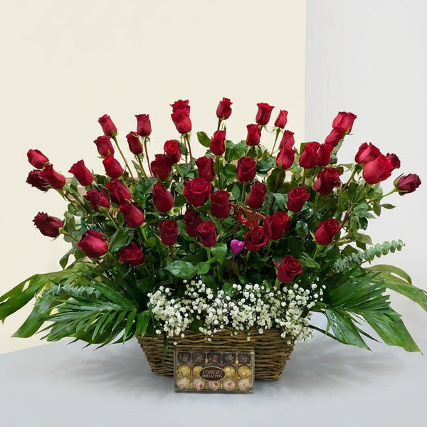Bouquet of red roses in a basket with a box of chocolates on a light gray background