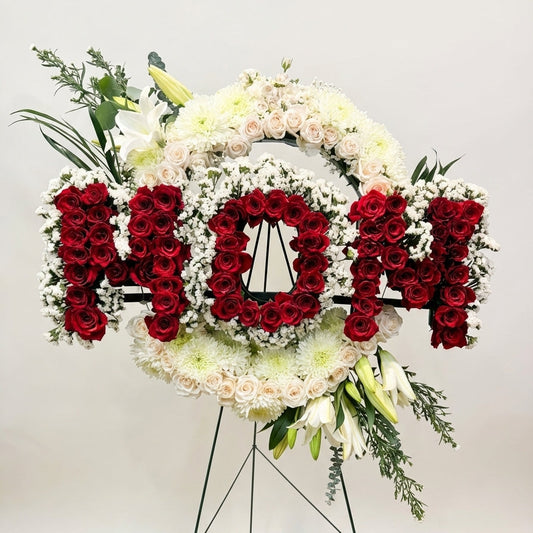 Floral arrangement with 'MOM' text on a stand against a white background