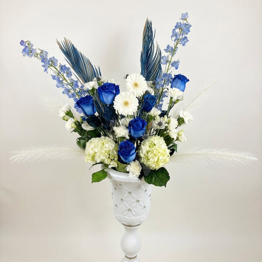 Floral arrangement with blue and white flowers in a white vase on a light background