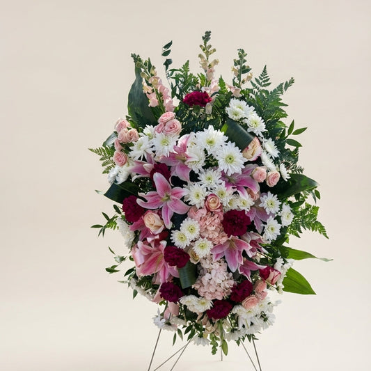 Floral arrangement on a stand with pink, white, and red flowers against a light background