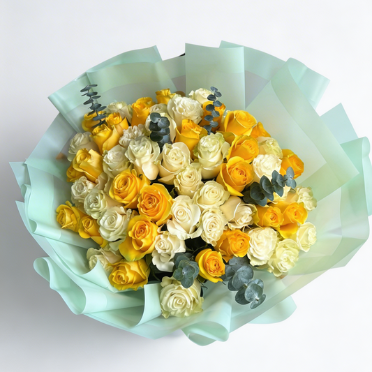 Bouquet of yellow and white roses with greenery on light blue paper against a white background