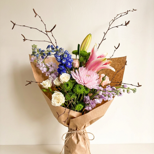Bouquet of flowers wrapped in brown paper on a light background