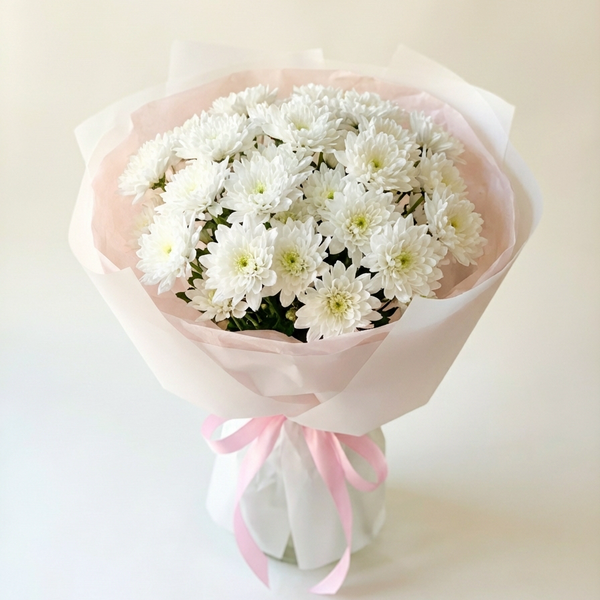 Bouquet of white flowers wrapped in pink paper on a light background