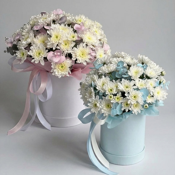 Two flower bouquets in white and light blue boxes with ribbons on a gray background