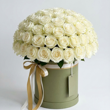 Bouquet of white roses in a green box with a gold ribbon on a light gray background