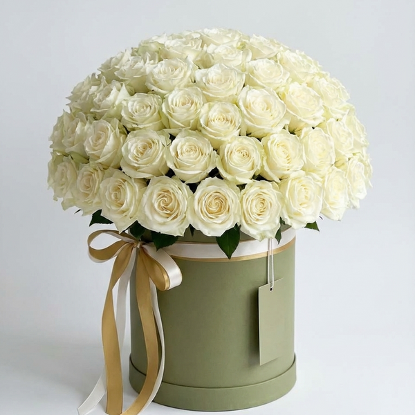 Bouquet of white roses in a green box with a gold ribbon on a light gray background