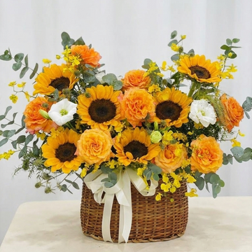 Bouquet of sunflowers and roses in a woven basket on a light background