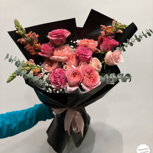 **Alt Text:**

"Elegant pink rose bouquet with eucalyptus and baby’s breath, wrapped in sleek black paper. A romantic and sophisticated floral arrangement perfect for special occasions like anniversaries, birthdays, and Valentine’s Day."