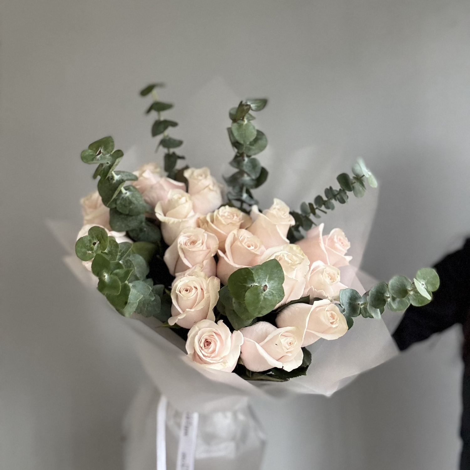 A delicate bouquet of soft pink blush roses and greenery, arranged elegantly with gentle petals and subtle hues of pale pink and cream.