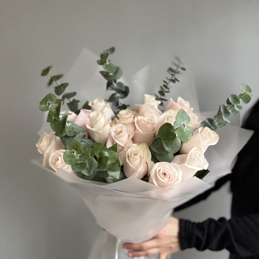 A delicate bouquet of soft pink blush roses and greenery, arranged elegantly with gentle petals and subtle hues of pale pink and cream.