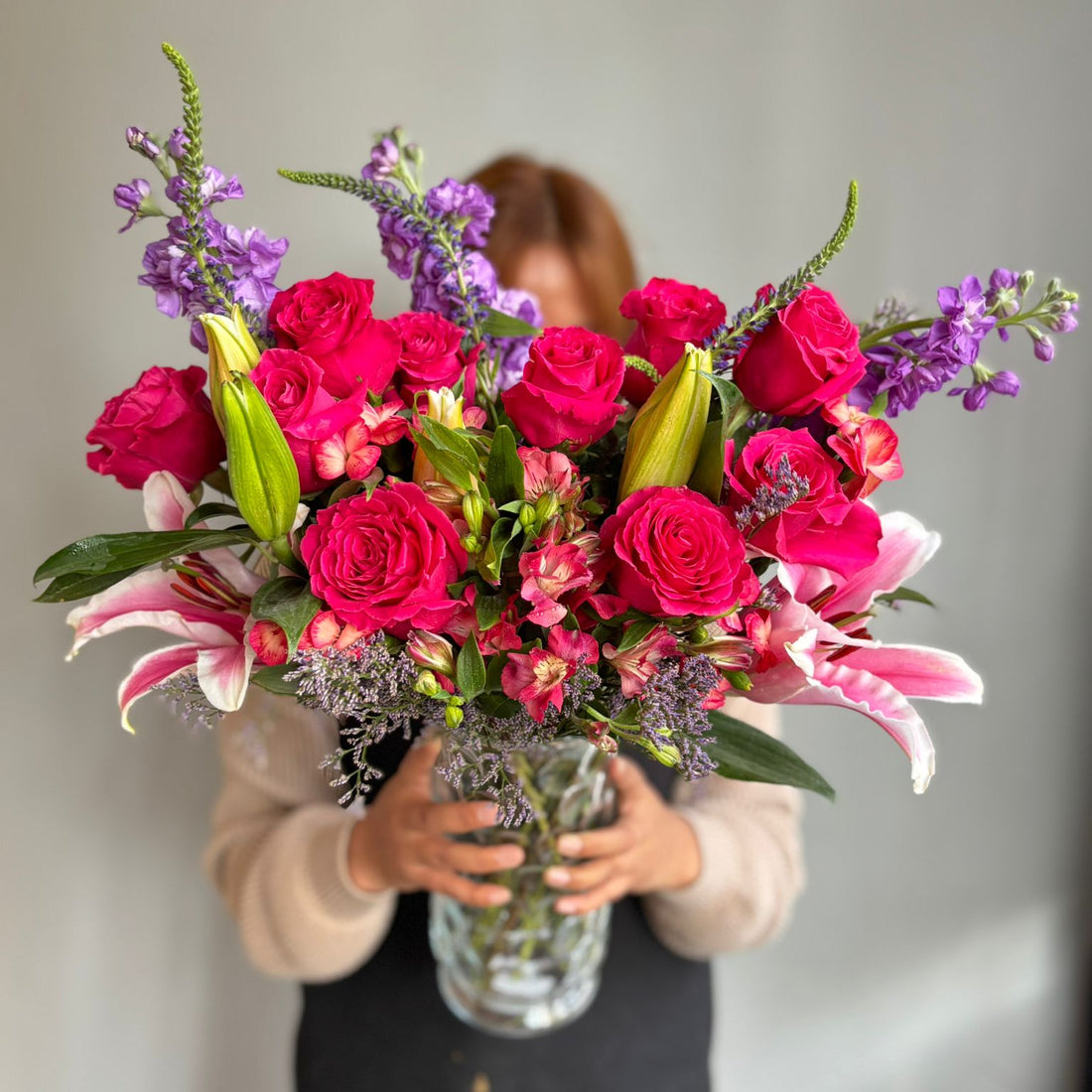 Person holding a vibrant bouquet of flowers against a plain background