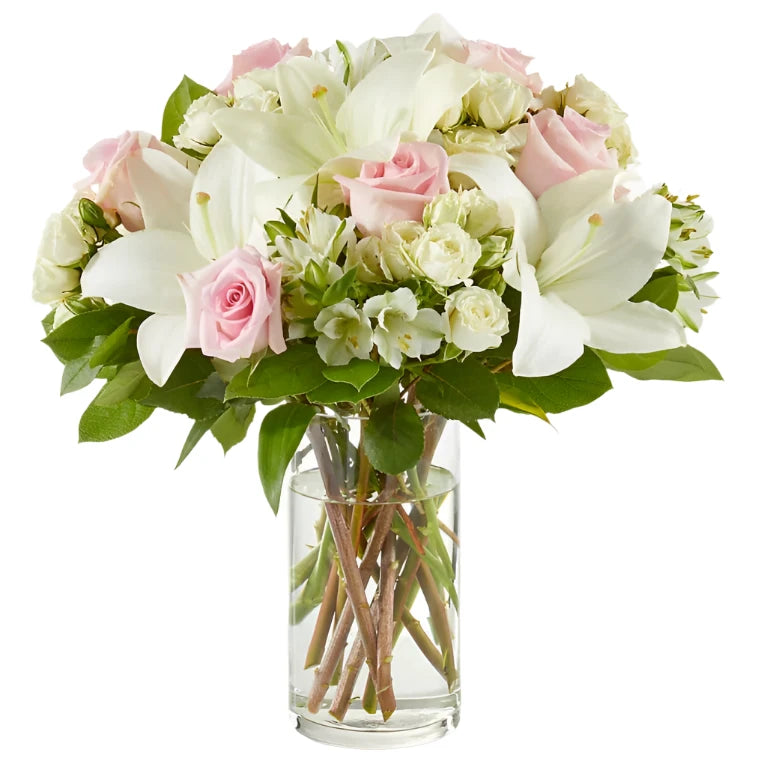 Elegant floral arrangement featuring white lilies, soft pink roses, and light daisies in a clear vase, symbolizing peace and remembrance